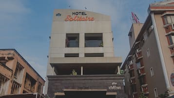 Un hotel llamado 'Solitaire' con una fachada moderna, una entrada destacada y una bandera en la parte superior.