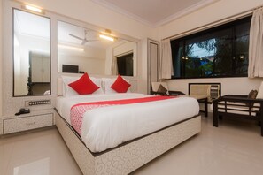 A hotel room with a large bed, two bedside tables, a desk, a chair, and a window with curtains. - Hotel O Solitaire (Mumbai)