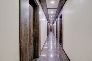 Un pasillo largo y estrecho con puertas a ambos lados, suelo brillante e iluminación empotrada en el techo.