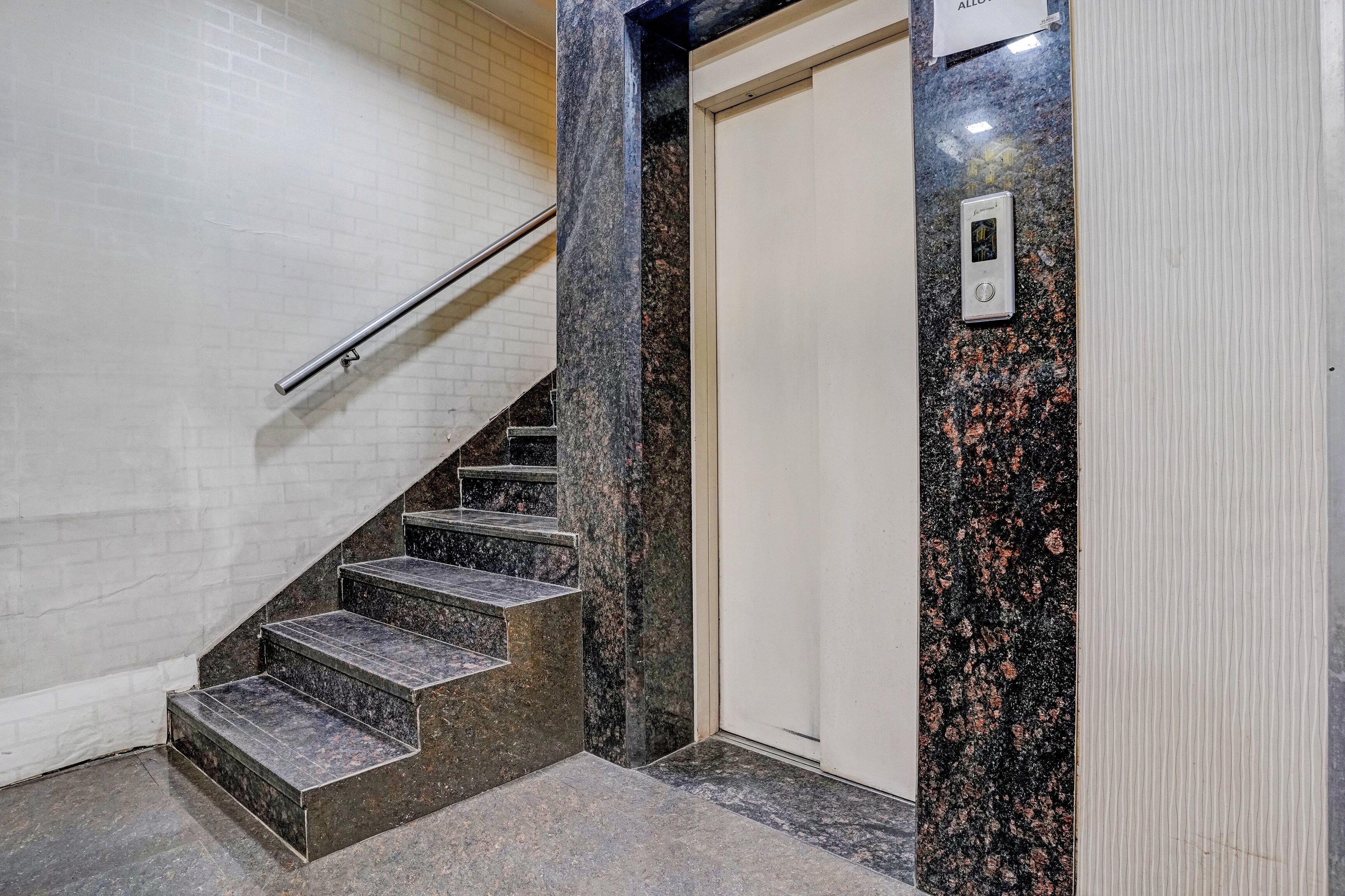 A staircase with a handrail leading to a door with a sign above it.