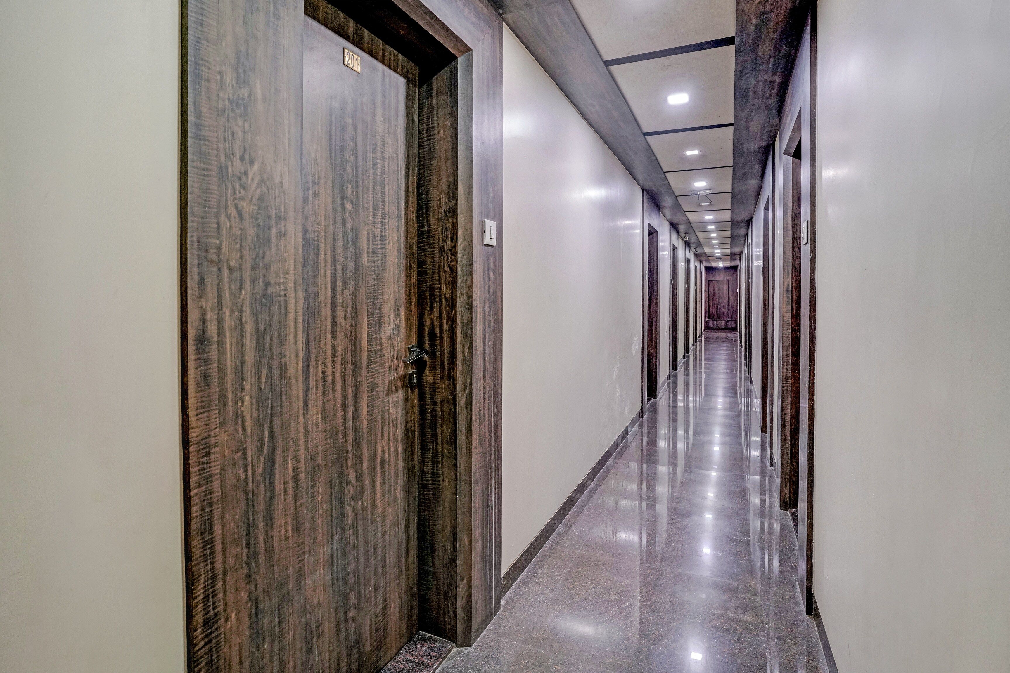 A long, narrow hallway with wooden doors and a shiny marble floor.