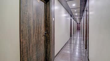 A long, narrow hallway with wooden doors and a shiny marble floor.