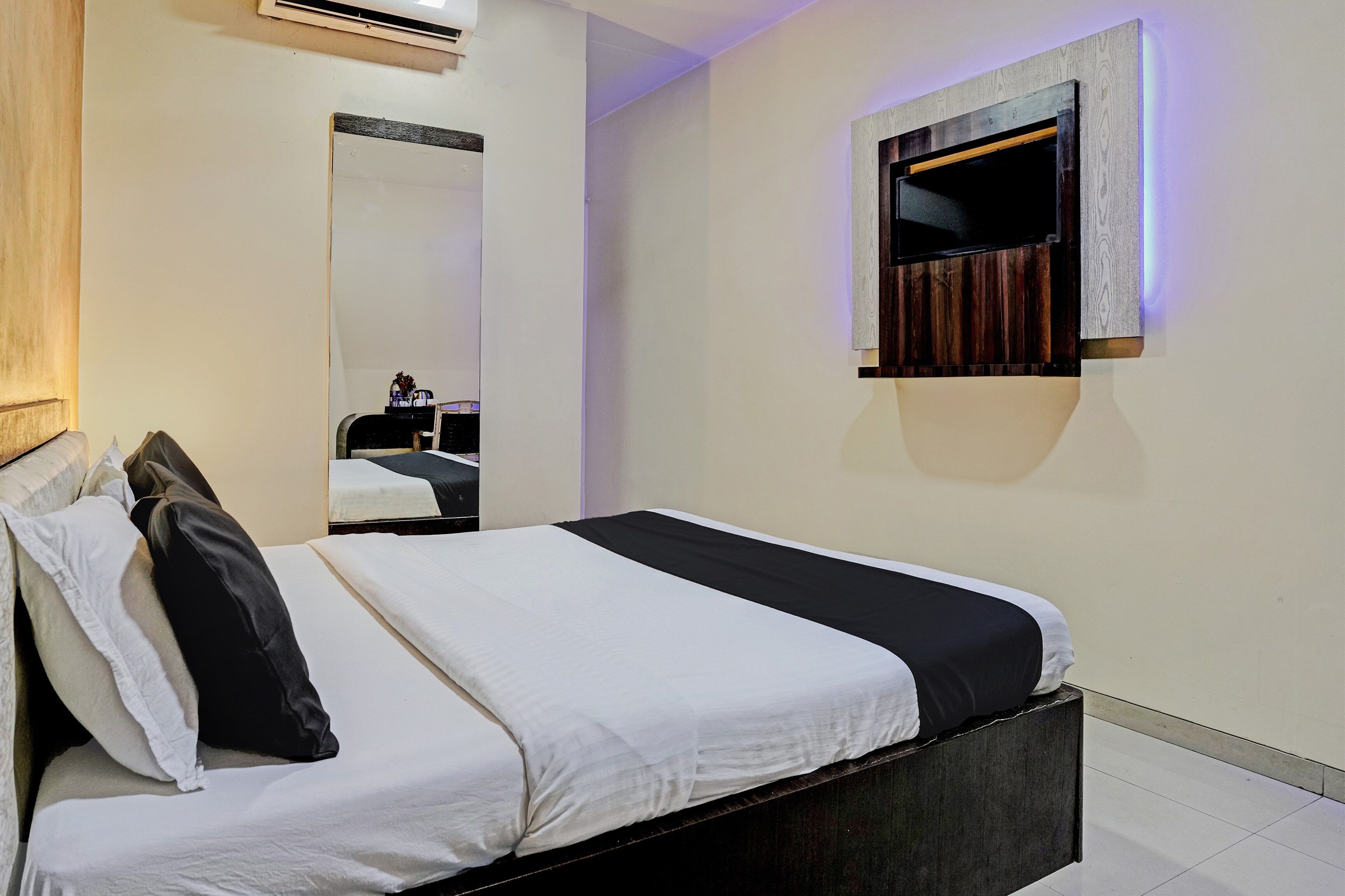 Une chambre d’hôtel avec un lit, un miroir et un luminaire fixé au mur.