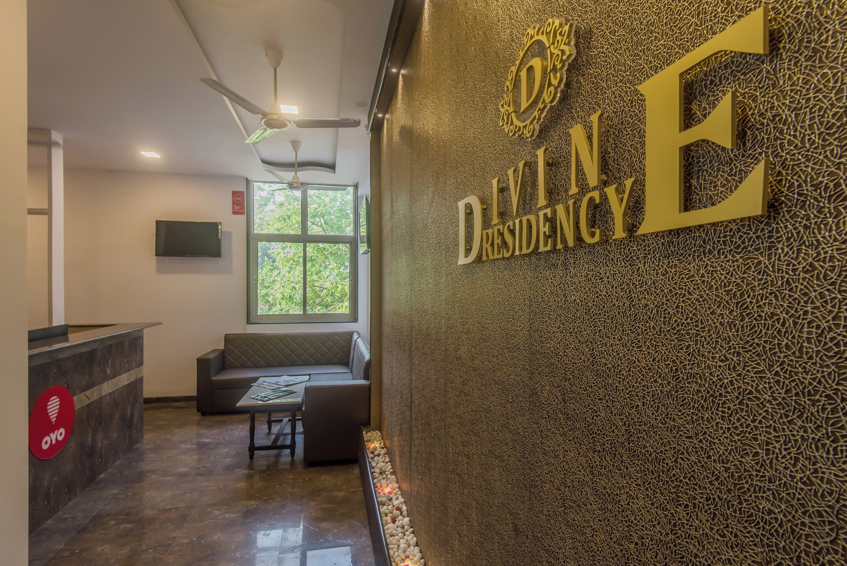 A reception area with a seating area, a reception desk, and a wall with the text 'DIVINE DRESENCY'.
