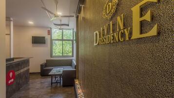 A reception area with a seating area, a reception desk, and a wall with the text 'DIVINE DRESENCY'.