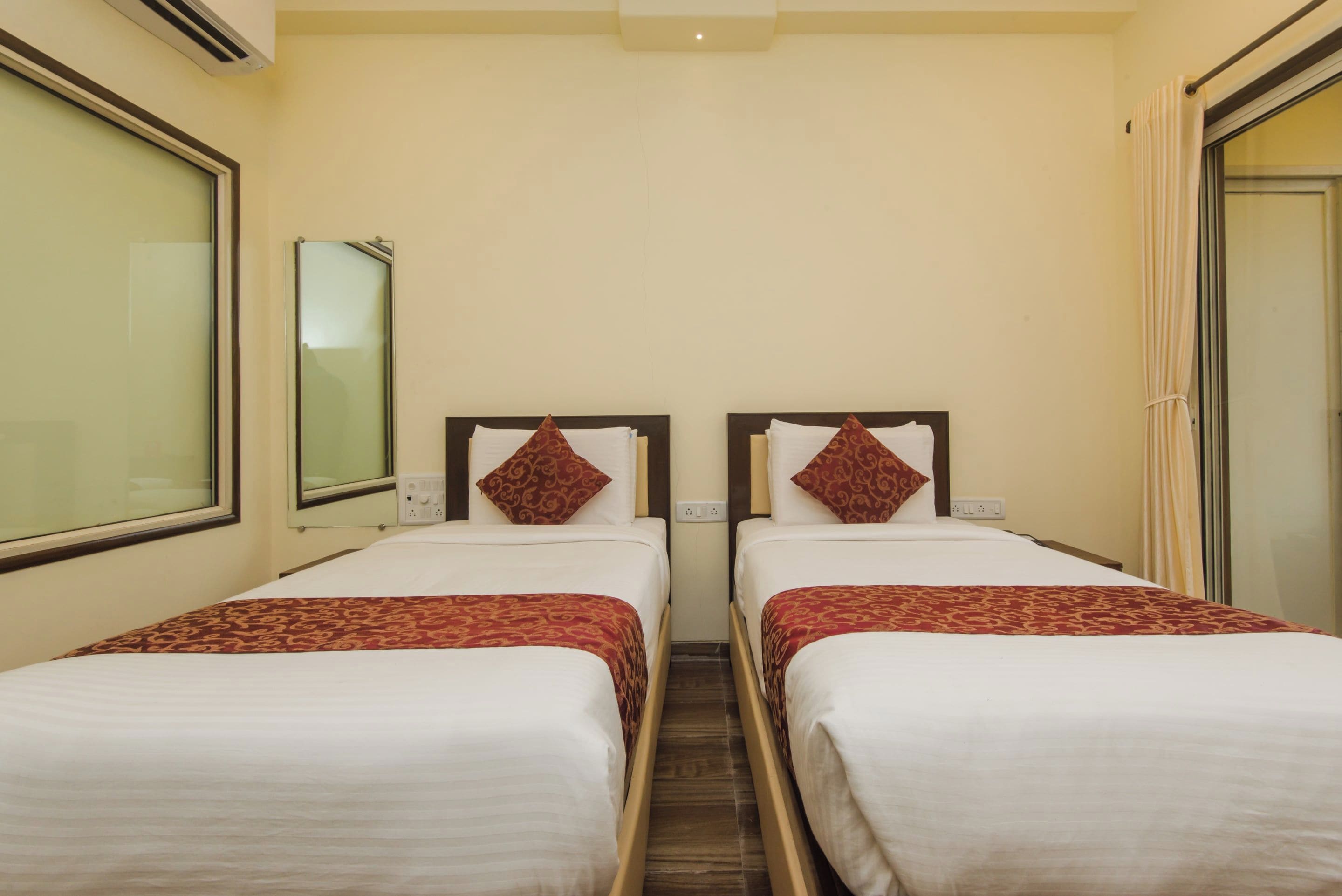 A hotel room with two single beds, each with a patterned bedspread and matching pillows.