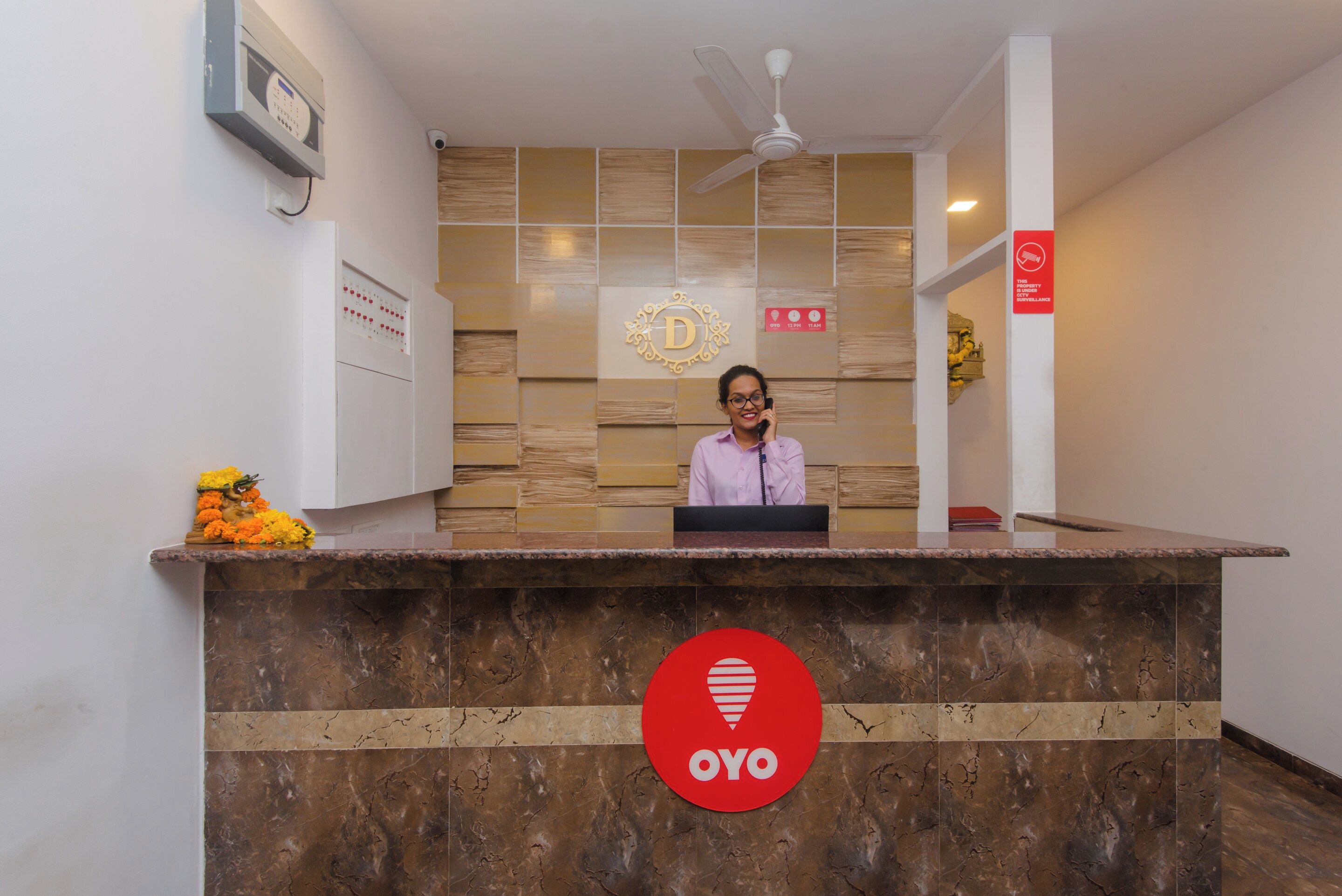 A reception desk with a logo, a clock, and a surveillance sign.