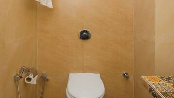 A bathroom with a white toilet, a shower with a handheld showerhead, and a towel rack.