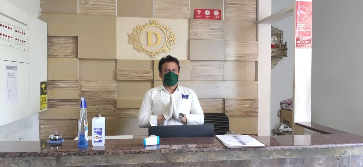 Una recepción de hotel con una placa de identificación, un cartel de circuito cerrado de televisión y un letrero que indica 'Pago antes del registro'.