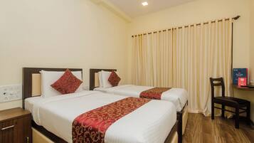 A hotel room with two beds, a wooden nightstand, a desk with a chair, and a television.