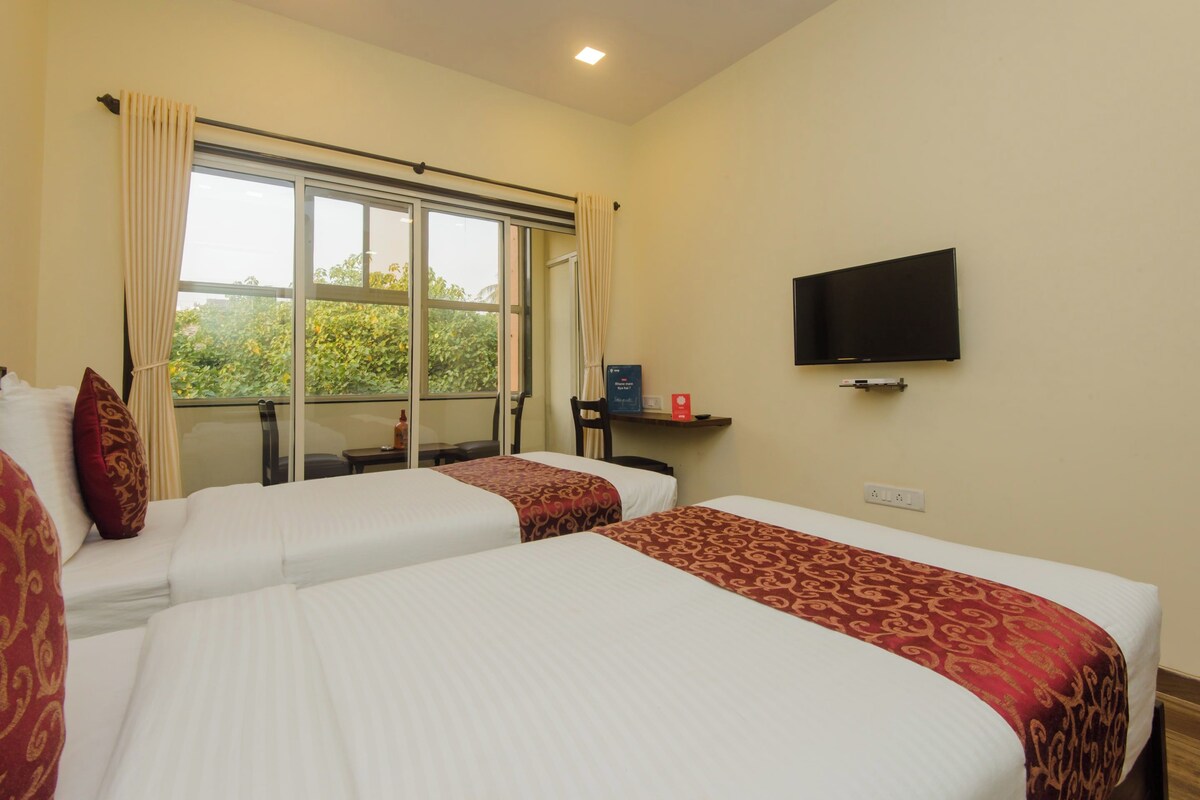 Habitación de hotel con dos camas, televisión y ventana con cortinas.