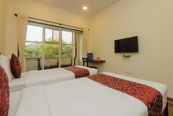 Habitación de hotel con dos camas, televisión y ventana con cortinas.
