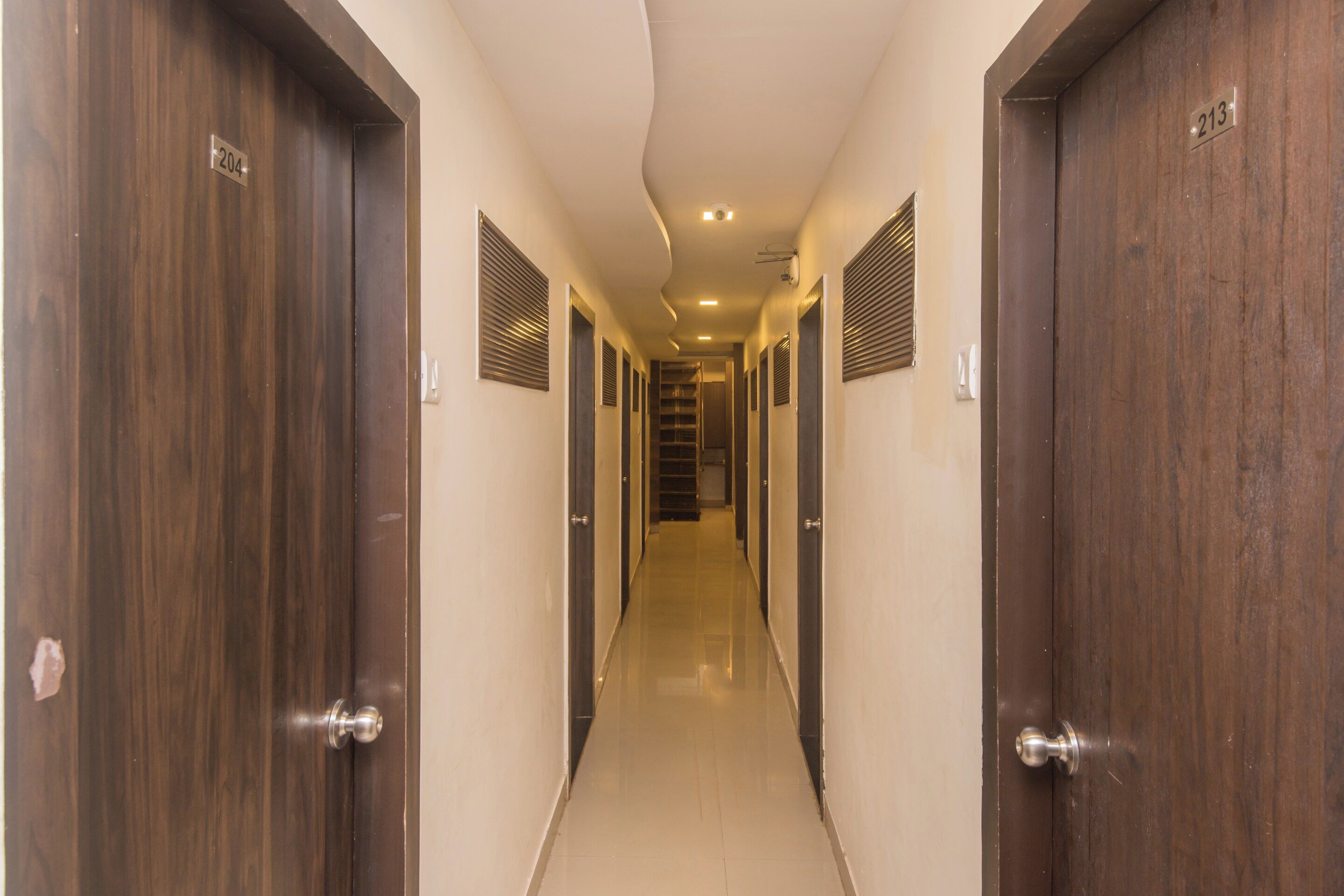Un pasillo de hotel con puertas de madera, cada una numerada.