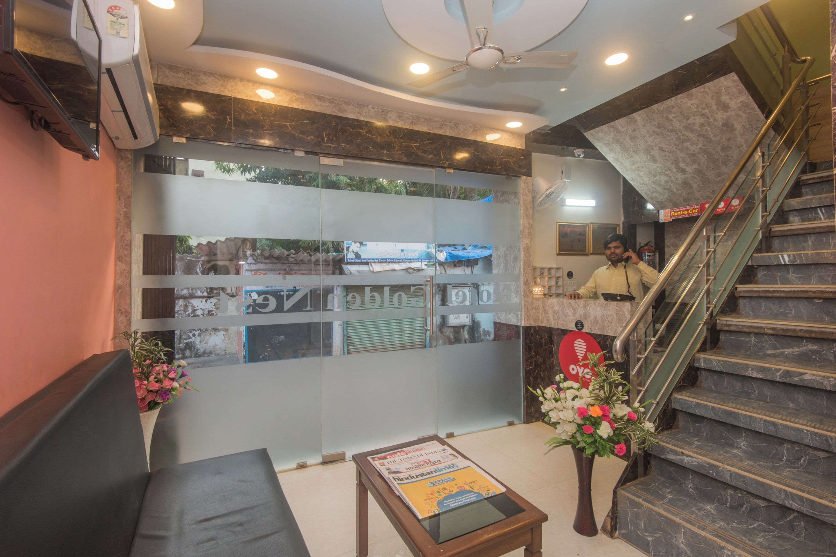 Zona de recepción con mostrador, escalera y pared con cuadros enmarcados.