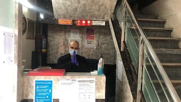 A reception desk with a person behind it, a sign for a Rent-a-Car service, and emergency contact numbers.