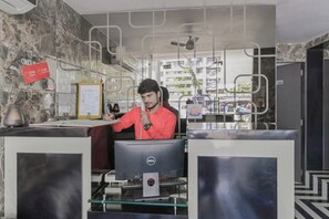Un mostrador de recepción con una computadora, un certificado enmarcado y un letrero de registro.