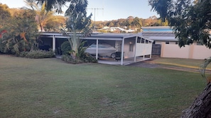 Uma casa com área externa coberta, um barco em um reboque e um gramado.