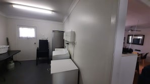 A room with a desk, chair, and a bed. There is a window with curtains, a ceiling fan, and a television mounted on the wall. - Walk to Beach Spacious yard for boats or 4x4 (Rainbow Beach)