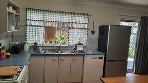 A compact kitchen with a sink, a stove, and a refrigerator. - Walk to Beach Spacious yard for boats or 4x4 (Rainbow Beach)