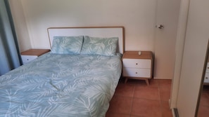 A bedroom with a bed, two nightstands, and a door. - Walk to Beach Spacious yard for boats or 4x4 (Rainbow Beach)