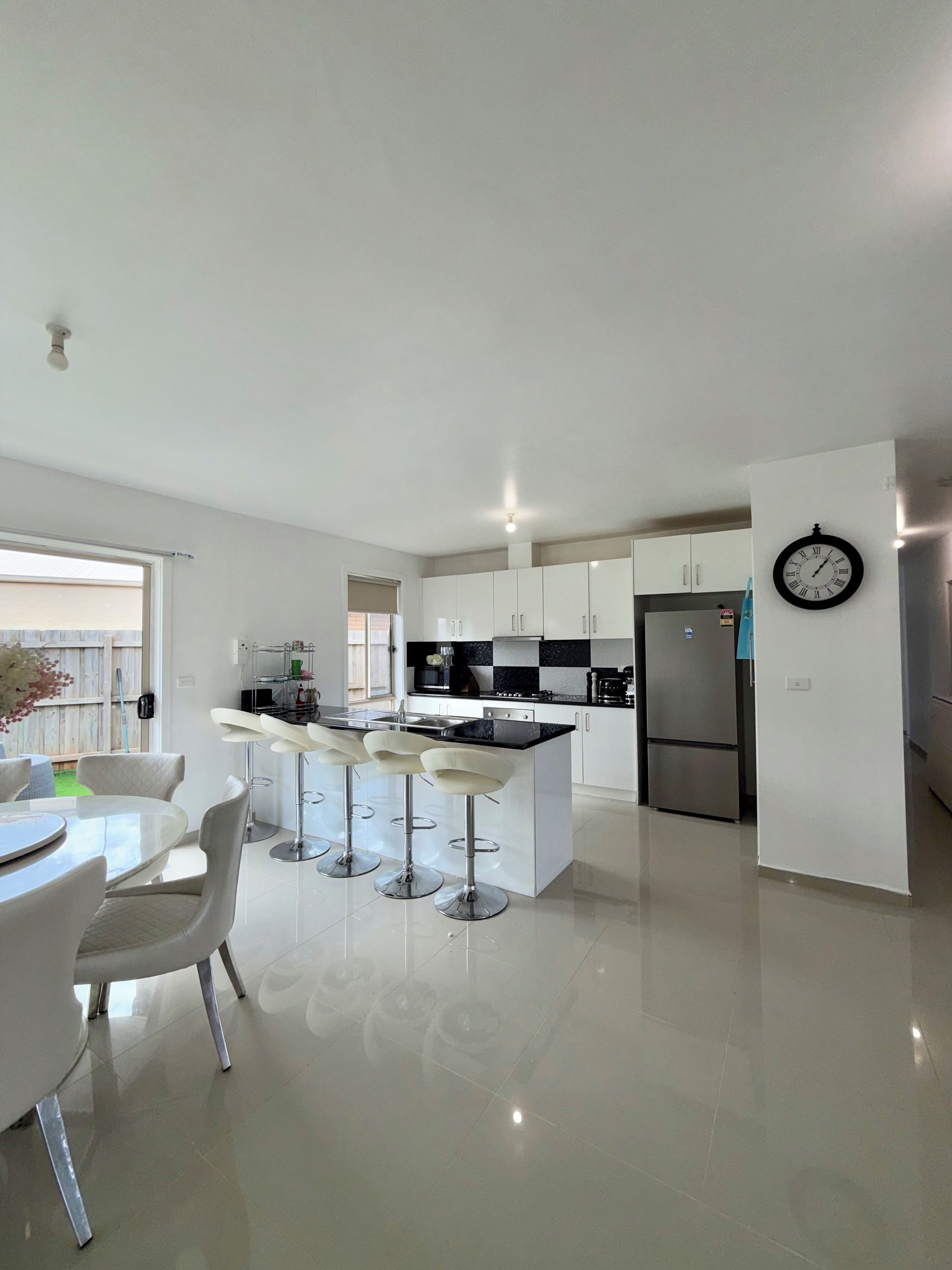 Cocina moderna con una isla central, taburetes de bar y un refrigerador.