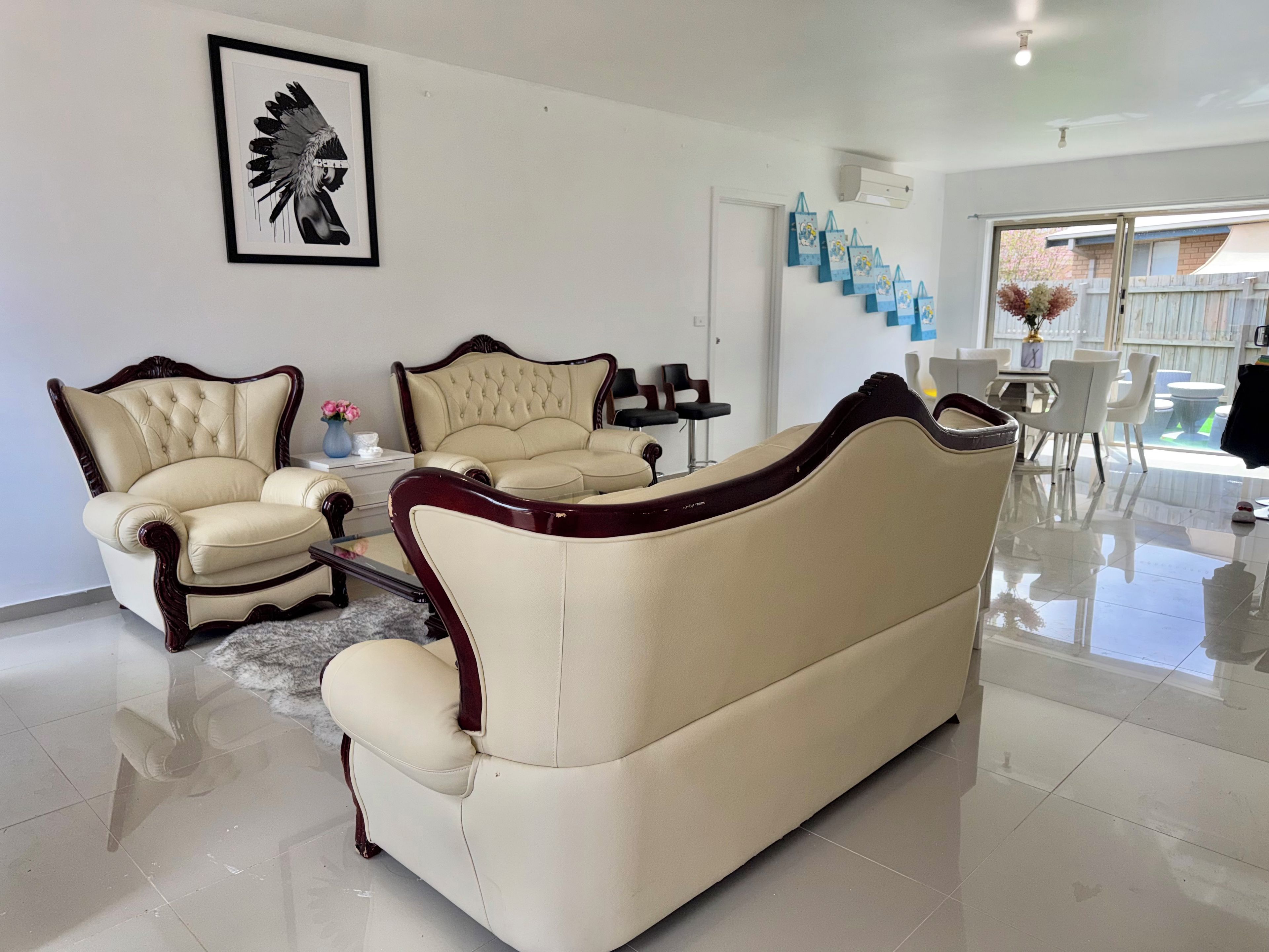 Una sala de estar con un sofá color crema, un sillón a juego y una obra de arte grande en la pared.