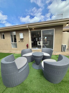 An outdoor seating area with wicker furniture and a green lawn.