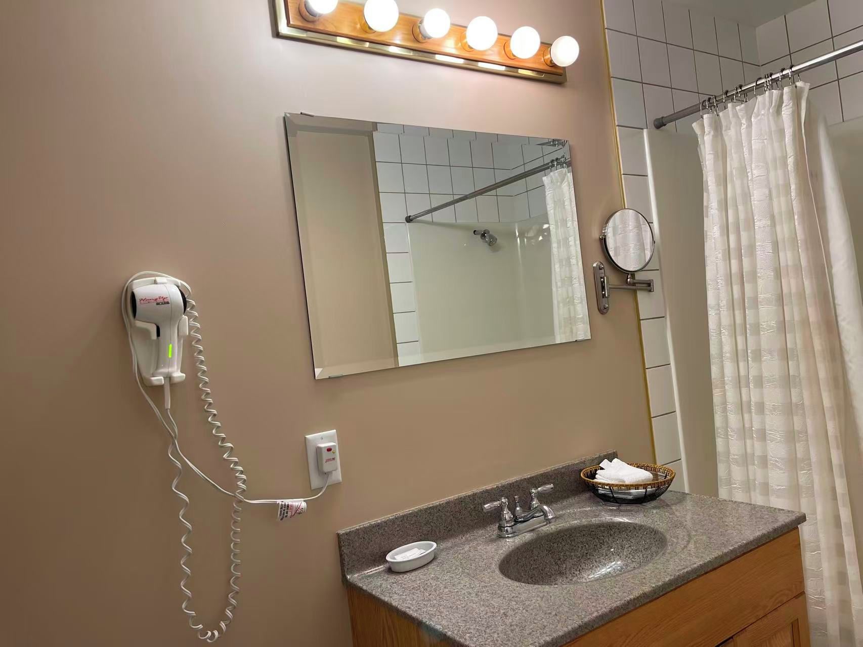 A bathroom with a sink, mirror, and hairdryer.
