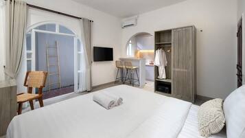 A hotel room with a bed, a desk, a chair, a wardrobe, and a TV.