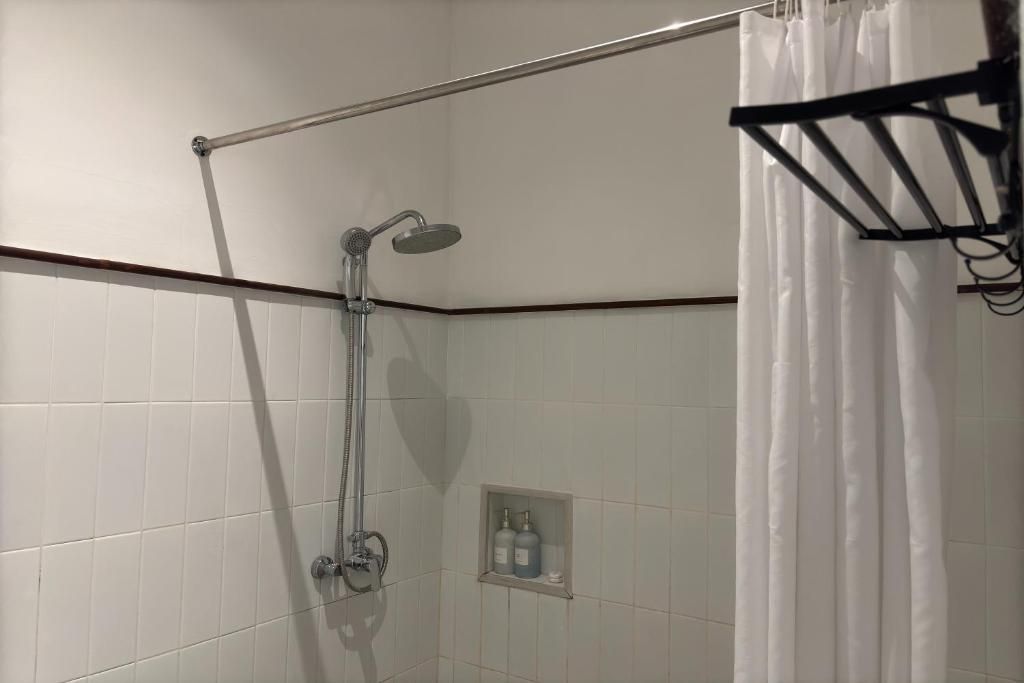 A shower area with a glass door, a towel rack, and a small shelf with toiletries.