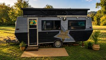 Un camping-car immobile, doté d’un toit fermé, d’une porte latérale et d’une petite fenêtre.