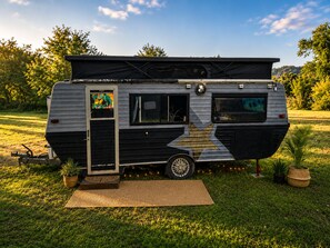 Un camping-car immobile, doté d’un toit fermé, d’une porte latérale et d’une petite fenêtre.