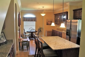 A kitchen with granite countertops, a stainless steel refrigerator, and wooden cabinets.