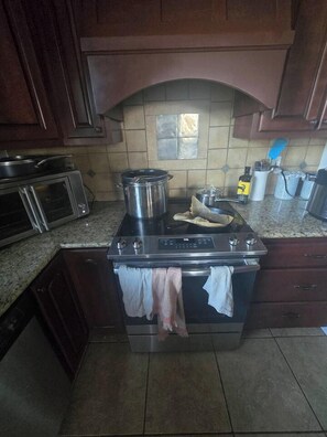 A kitchen with a stove, oven, microwave, and cabinets.