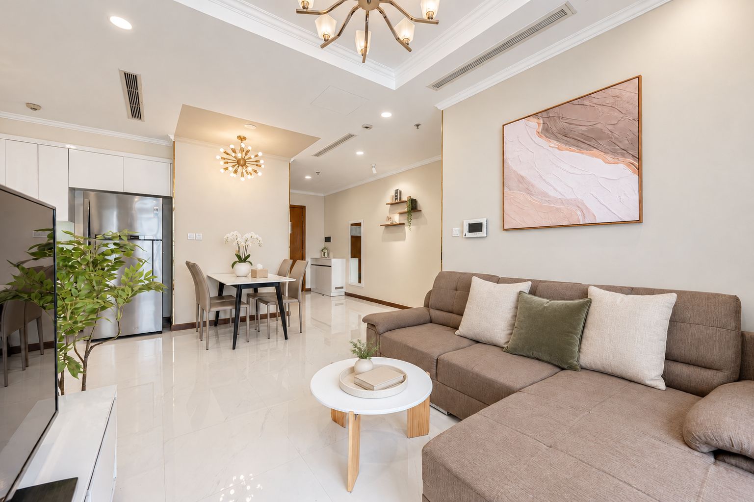 A modern living room with a sofa, a dining table, and a kitchen in the background.