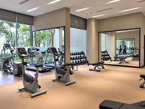 Un gimnasio con cintas de correr, elípticas y pesas libres.