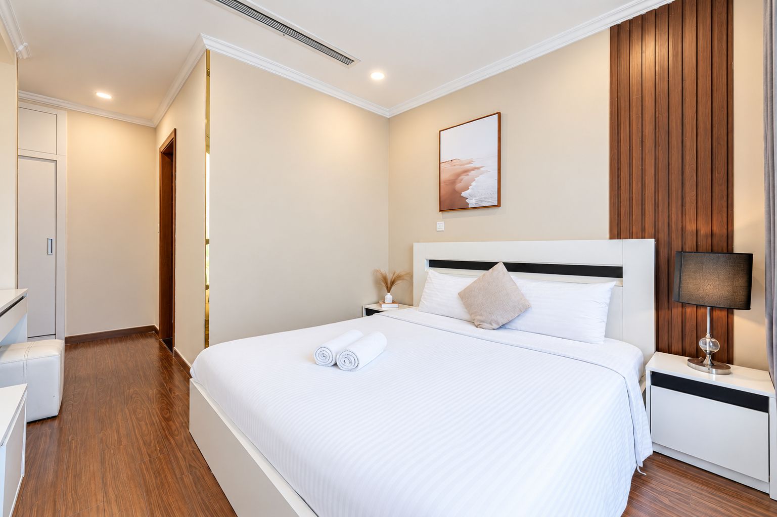 Habitación de hotel con una cama grande, una mesita de noche con lámpara, una obra de arte en la pared y un revestimiento de pared de madera.
