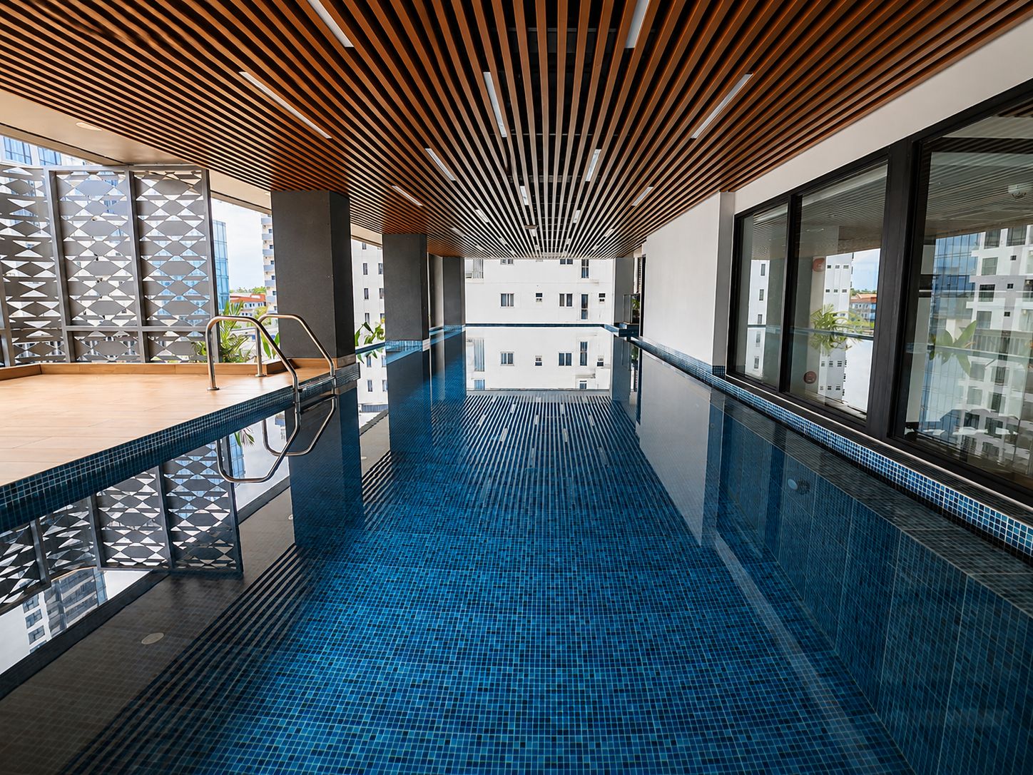 Ein modernes Hallenbad mit Holzbalkendecke und Glaswänden.
