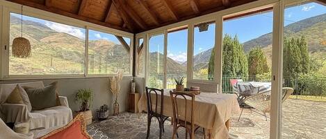Une terrasse couverte avec un sol en pierre, une table et des chaises, et une vue sur la campagne.