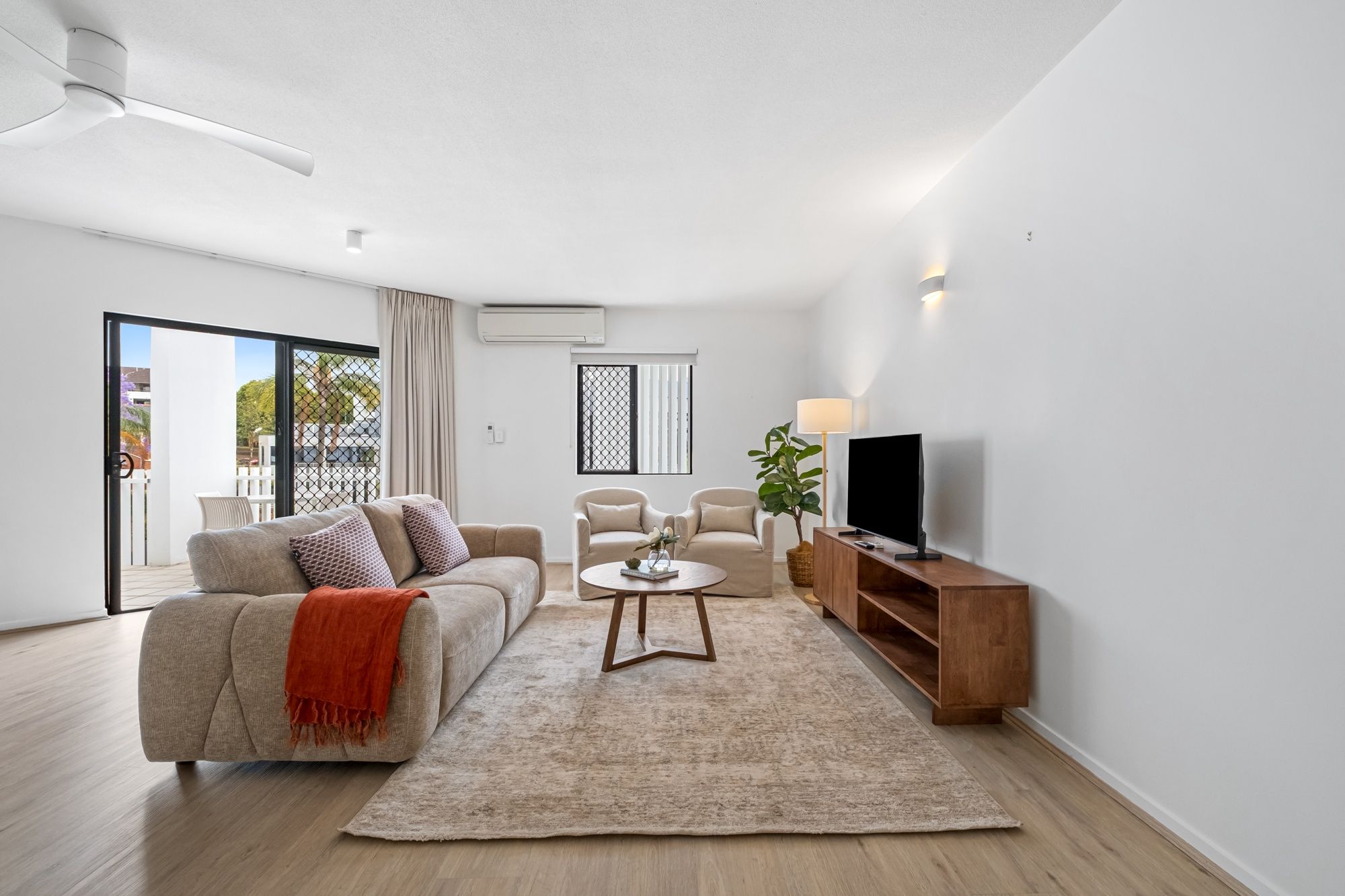 A modern living room with a sofa, chairs, a coffee table, a TV, and a wooden cabinet.