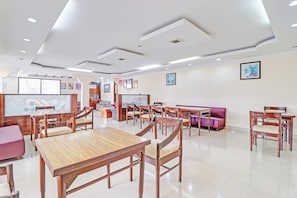 Un amplio comedor con mesas y sillas de madera, un sofá y obras de arte colgadas en la pared.
