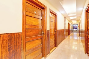 Un pasillo con puertas de madera, piso de baldosas e iluminación empotrada en el techo.