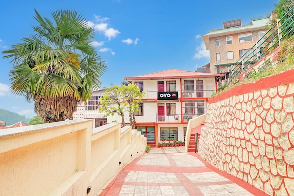 A hotel with a red and white facade, a staircase leading to the entrance, and a palm tree in the foreground.