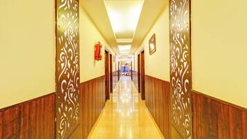 A hotel corridor with wooden paneling, a fire extinguisher, and a ceiling light fixture.
