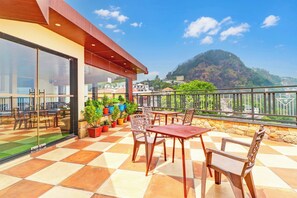 A terrace with a checkered floor, outdoor seating, and potted plants.