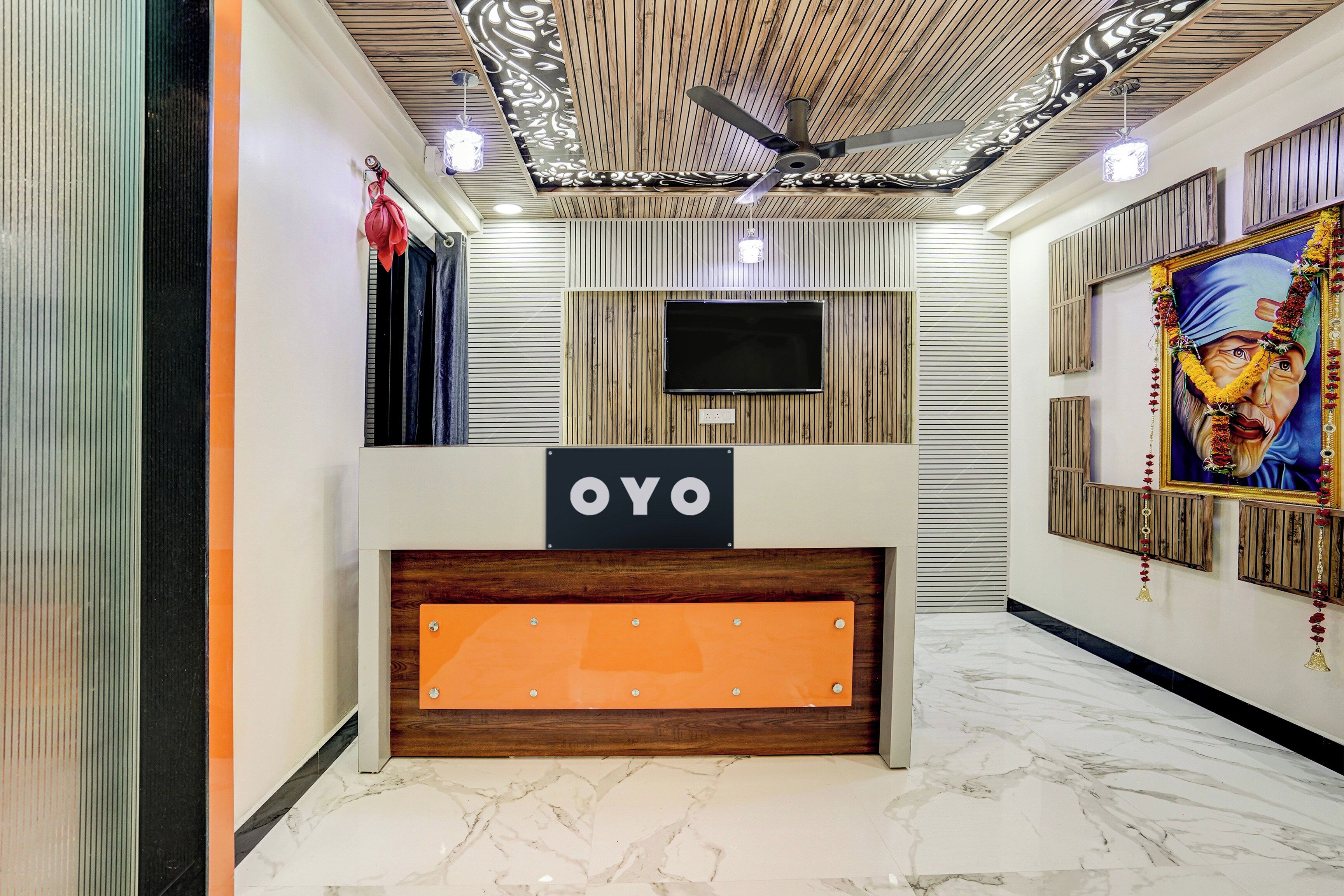 Un comptoir d’accueil avec une enseigne indiquant « OYO », dans un intérieur moderne agrémenté de lambris en bois et d’un téléviseur à écran plat fixé au mur.