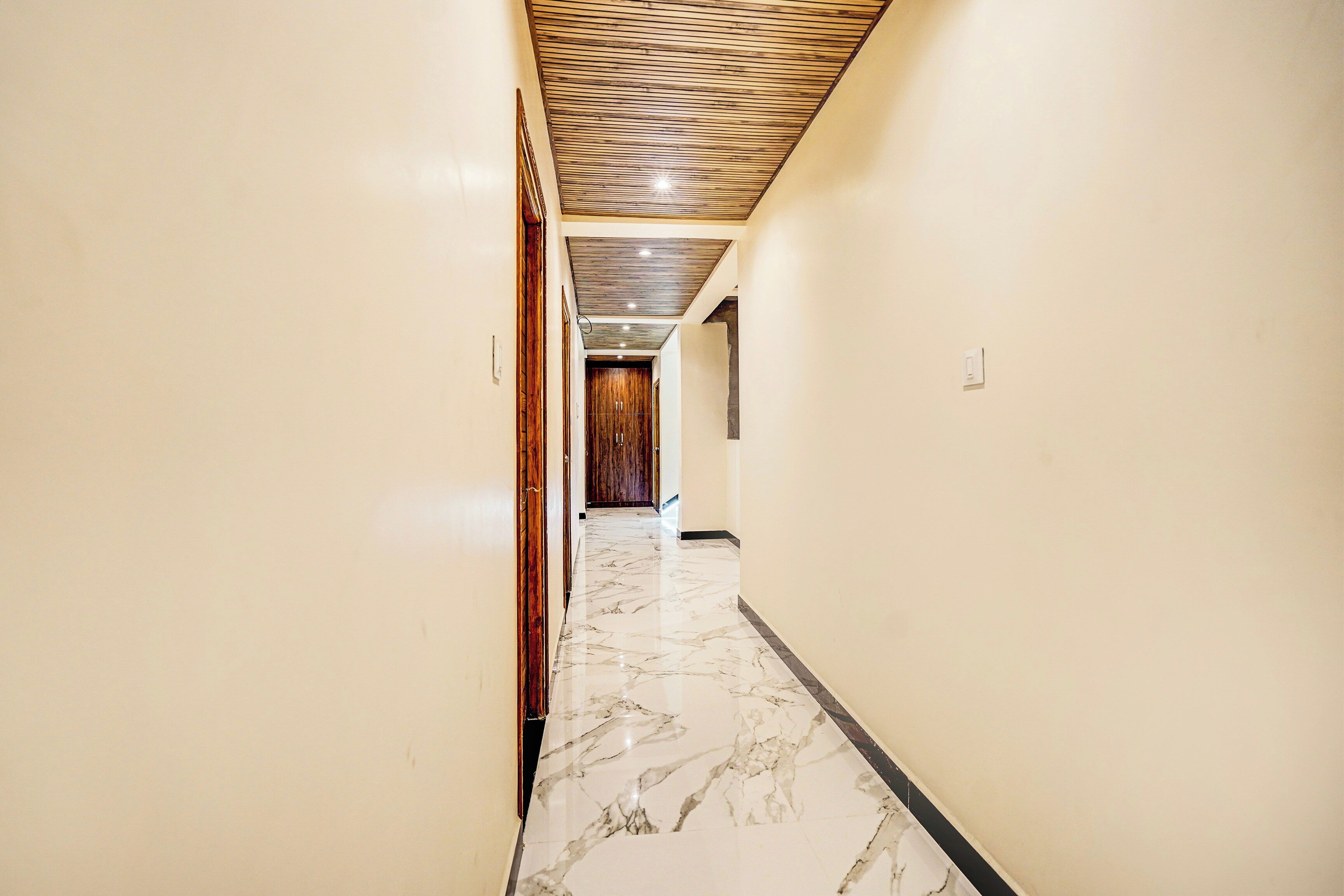 A long, narrow hallway with marble flooring and wooden paneling on the ceiling.