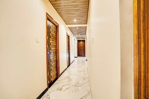 Un pasillo con suelo de mármol, puertas de madera y techo con listones de madera.