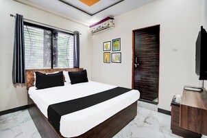 Un dormitorio con cama, ventana con cortinas, una puerta y una obra de arte colgada en la pared.