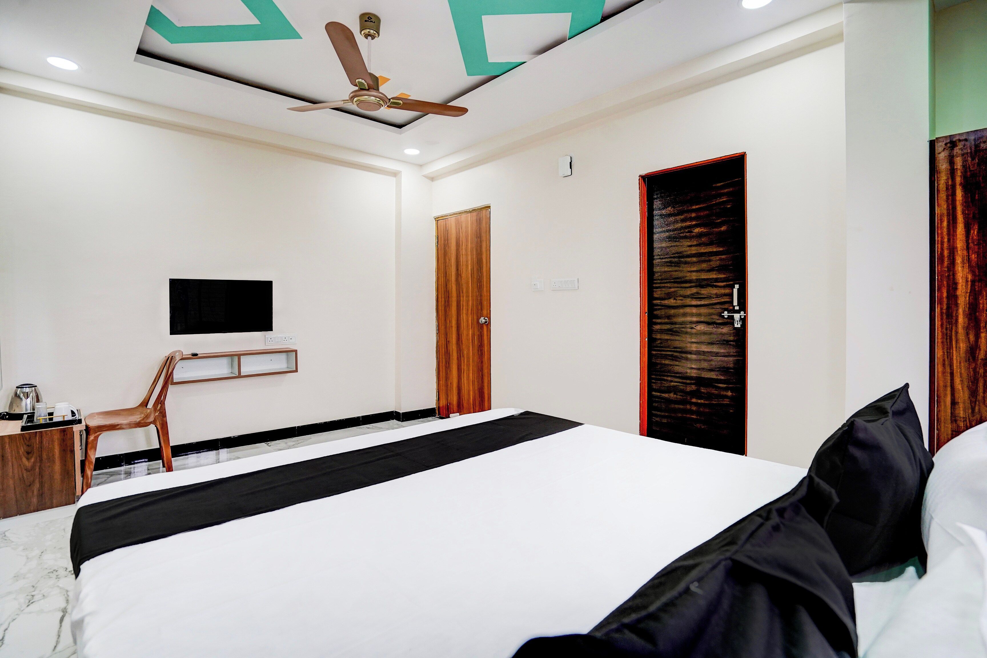 Una habitación de hotel con una cama, un escritorio, una silla, un televisor y una puerta.